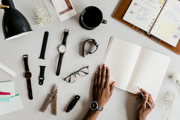 Black man writing on a notebook surrounded by daily essentials