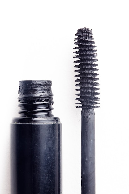 Black mascara and brush isolated on white. Cosmetic detail close up