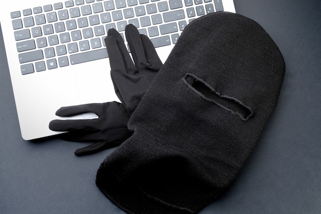 Black mask and black gloves on a laptop