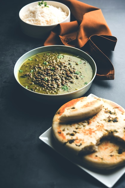 Black Masoor Dal fry or Dhaba Style Sabut Red Lentil dhal tadka in green curry, served in a bowl. selective focus