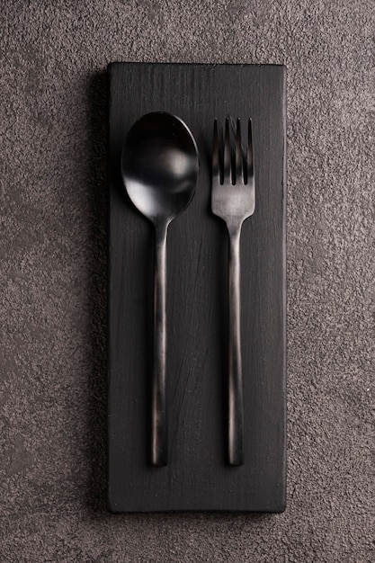 Black matte spoon and fork set. vertical photo close-up. flat lay.