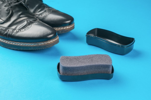 Black men's shoes and foam sponge on a blue background