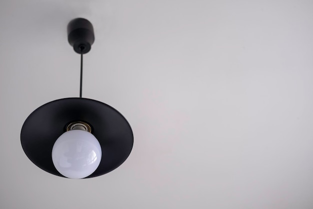 白い天井に省エネ電球を備えたロフトスタイルの黒い金属ランプ