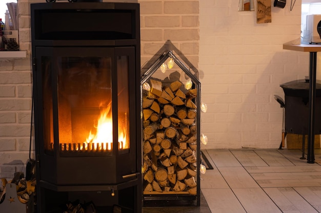 Black metal stove fireplace with wood in a woodpile the interior of a private village house Heating and heating of the house with firewood the heat of the fire from the hearth