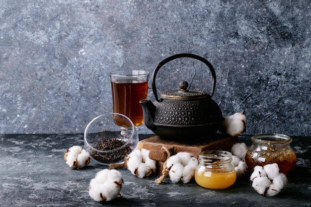 A black metal teapot and a cup of tea in glass cup