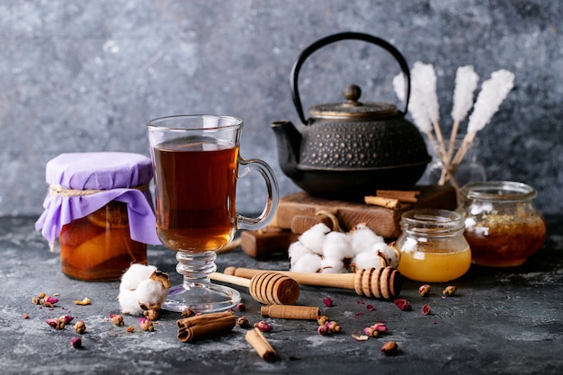 A black metal teapot and a cup of tea in glass cup