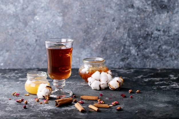 A black metal teapot and a cup of tea in glass cup