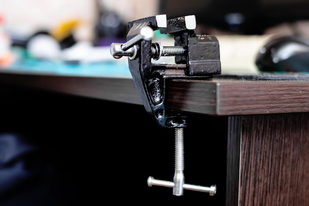 Black metal vise on edge of wooden table