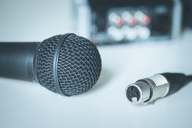 Black microphone and audio cable mixer in the blurry background