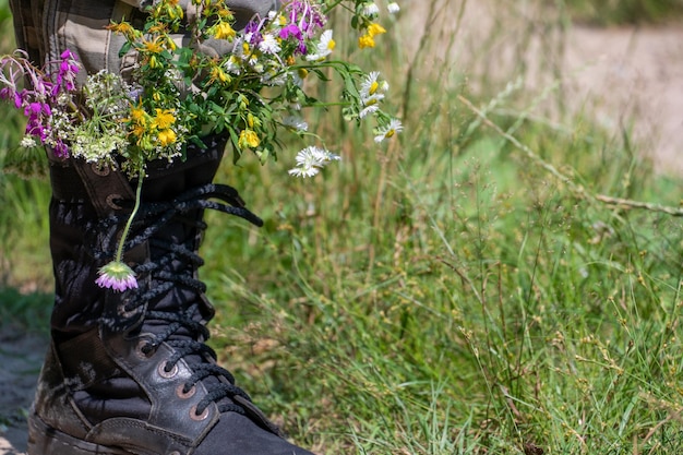 Black military boots with flowers concept flowers instead of\
bullets and war ending the war in ukraine the surrender of the\
russian army and the withdrawal of troops from the territory of\
ukraine