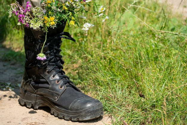 Black military boots with flowers Concept flowers instead of bullets and war Ending the war in Ukraine The surrender of the Russian army and the withdrawal of troops from the territory of Ukraine