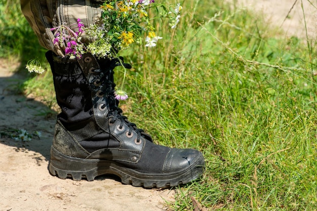 Black military boots with flowers Concept flowers instead of bullets and war Ending the war in Ukraine The surrender of the Russian army and the withdrawal of troops from the territory of Ukraine