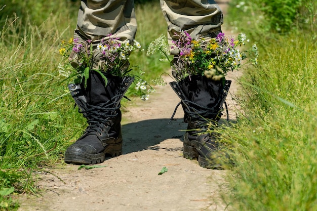 Black military boots with flowers concept flowers instead of\
bullets and war ending the war in ukraine the surrender of the\
russian army and the withdrawal of troops from the territory of\
ukraine