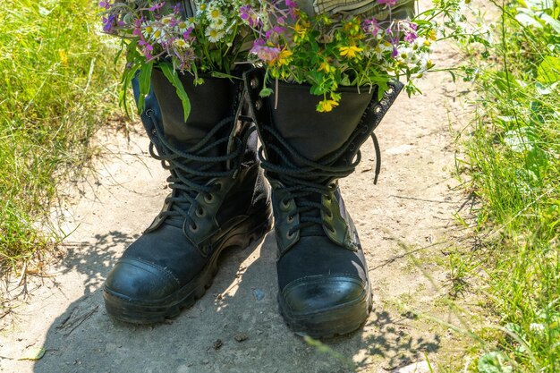 Black military boots with flowers Concept flowers instead of bullets and war Ending the war in Ukraine The surrender of the Russian army and the withdrawal of troops from the territory of Ukraine