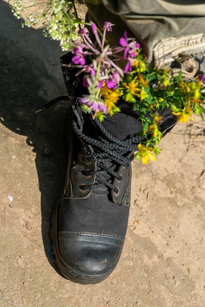 Black military boots with flowers Concept flowers instead of bullets and war Ending the war in Ukraine The surrender of the Russian army and the withdrawal of troops from the territory of Ukraine