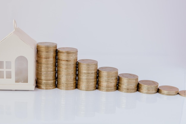 A black model of a car and house with coins in the form of a histogram on a white background Concept of lending savings insurance