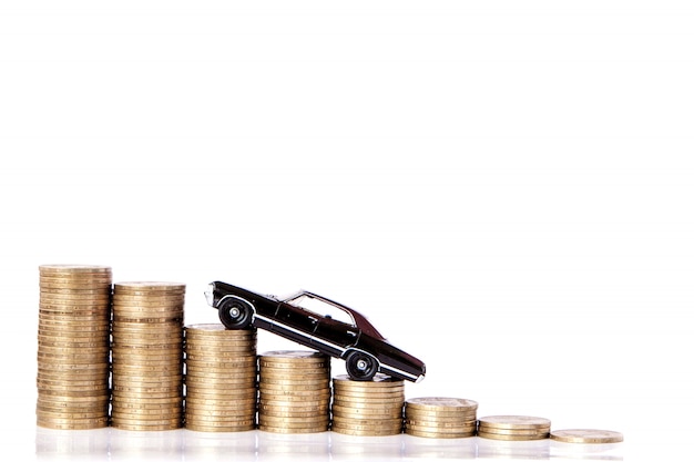 A black model of a car with coins in the form of a histogram on a white background. Concept of lending, savings, insurance.