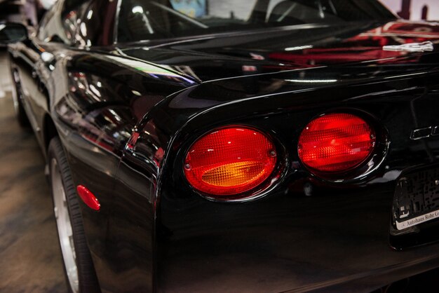 Black modern automobile with lights parked indoors at car show