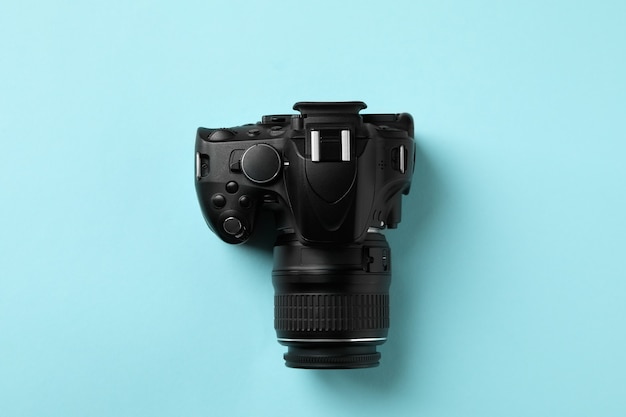 Black modern camera on blue background, top view