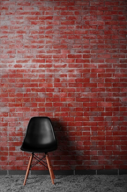 벽돌 벽 배경에 검정 현대 의자