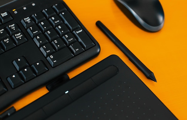 Черные современные офисные инструменты клавиатура мышь рисование стилусом на желтом столе