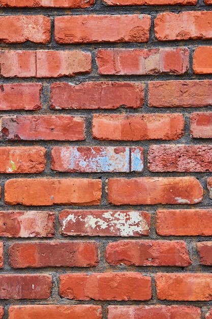 Black mortar between fading red bricks on wall with crumbling texture