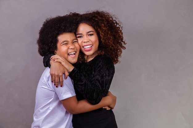 Black mother and son hugging on gray background