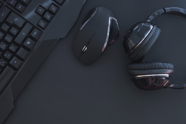 Photo black mouse, the keyboard, the headphones are isolated on a dark background, the top view. flat lay gamer background