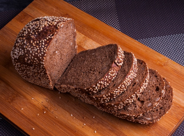 Black multigrain bread sliced on a bamboo board with sesame and sunflower seeds