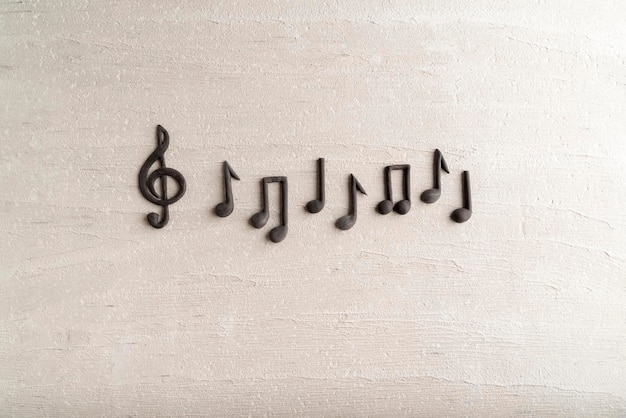 Black music violin clef sign and note on rough beige surface. G-clef. Treble clef. Space for text