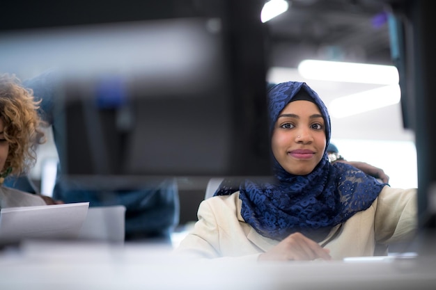 black muslim female software developer working together with her multiethnics business team using computer while writing programming code at modern startup office