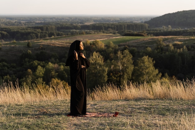 Black muslim woman praying on the carpet. solat praying on the
beautiful hill. salah traditional pray.