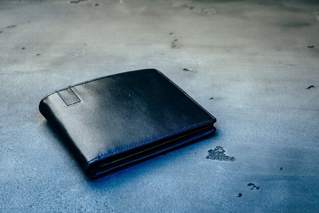 灰色のコンクリートに黒い新しい革の財布