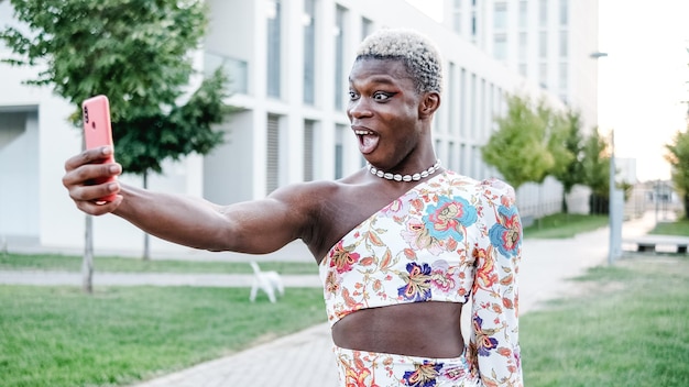 Black Nonbinary and young person is taking a selfie outdoor