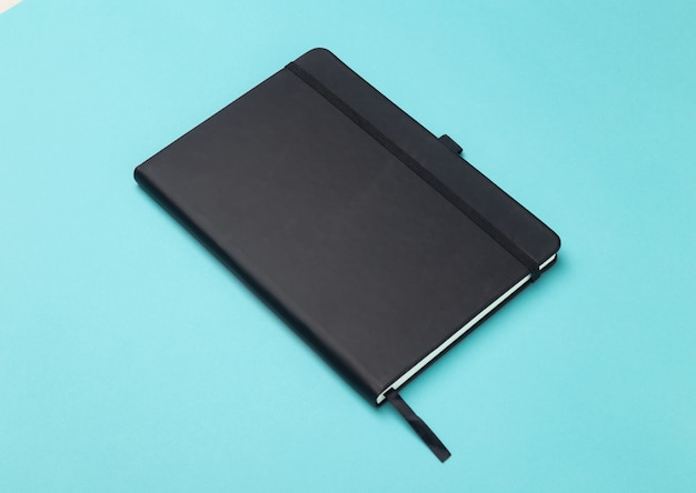 Black notebook isolated on blue background.