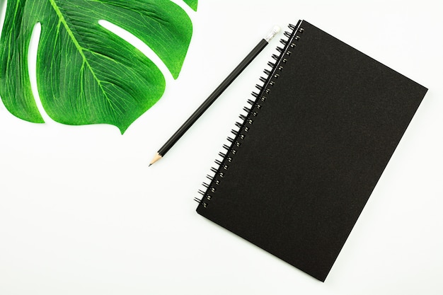 Black notebook and a pencil on white desk with copy space. - top view.