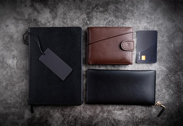 Black notebook wallets credit cards and blank price tag top view flat lay on dark background