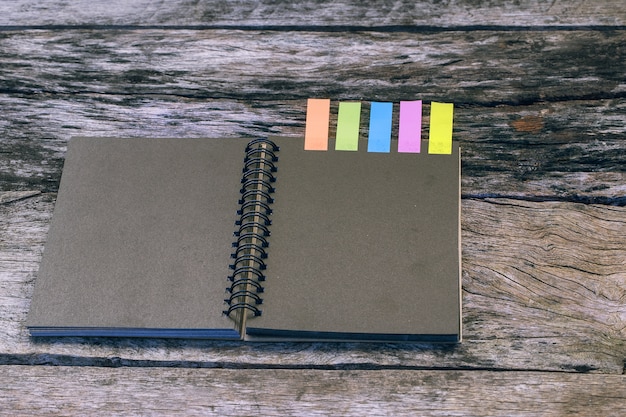 Black notebook with colors note tab on wooden table. Case study concept