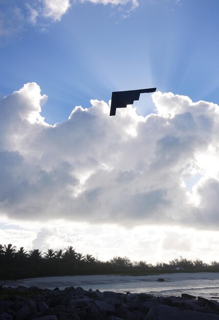 Photo a black object is flying above a cloud with the sun shining through it.