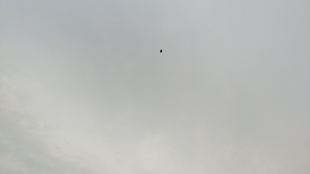 A black object is flying through the clouds in the sky.