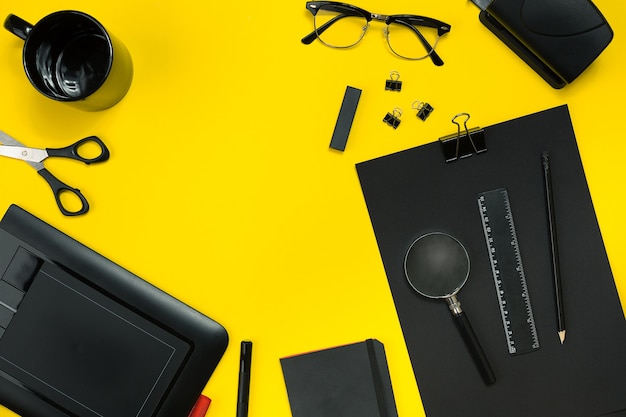 Black objects from the office on a yellow background. Work and creativity. Social media concept hero header image. Top view. Still life. Copy space