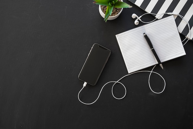 Black office workspace with supplies on dark background, flat lay