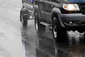 Photo black offroad car with hindcarriage behind on wet asphalt road at rainy day