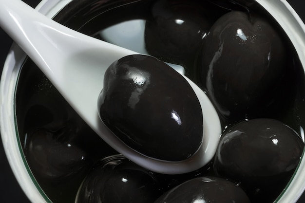 Black olive in spoon complete jar of olives