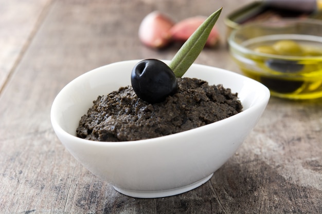 Black olive tapenade with anchovies, garlic and olive oil on wooden table