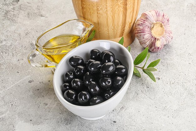 Фото Черные оливки в миске с маслом и веткой