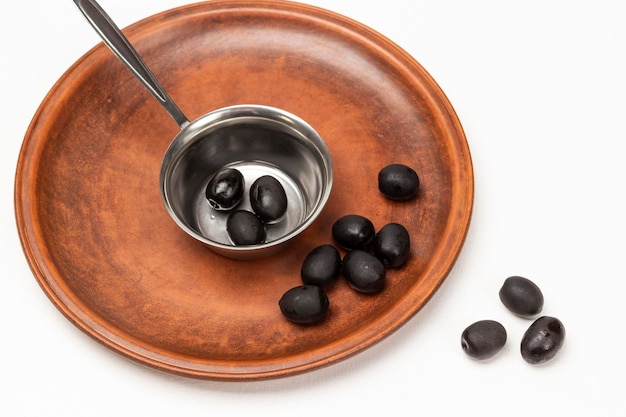 Black olives in a metal bowl and on a ceramic plate