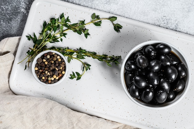 Black olives on a white chopping Board. Gray background. Top view