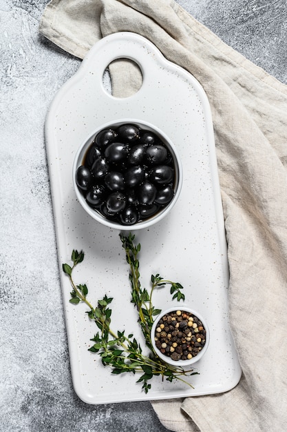 Black olives on a white chopping Board. 