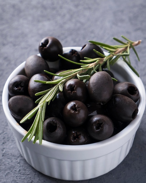 Black olives with rosemary in a bowl Closeup